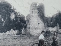 Le château vers 1900  La photographie d'époque (début du XXe siècle) met en scène des visiteurs avec des bicyclettes devant l'une des tours circulaires en pierre, alors massivement recouverte de lierre et de végétation avant les grandes campagnes de restauration modernes